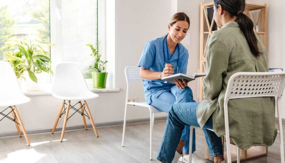 Smiling doctor writing notes with patient