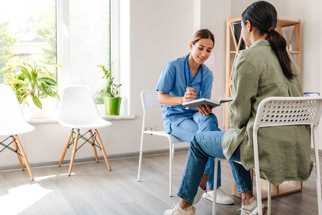 Smiling doctor writing notes with patient
