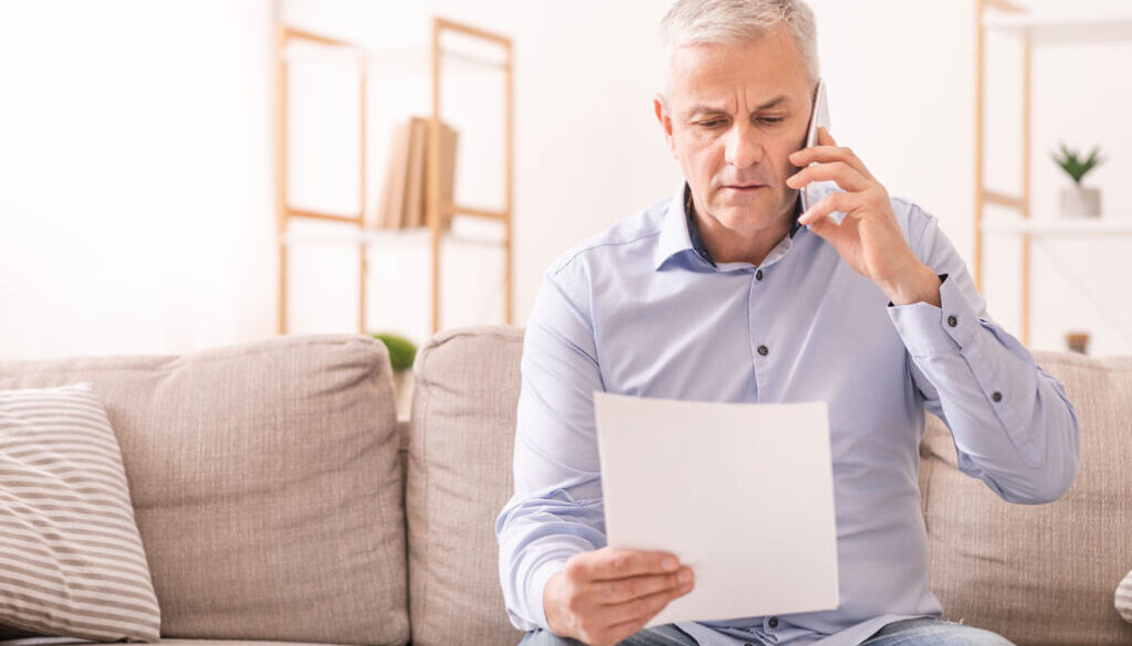 Man talking on phone while looking at paper
