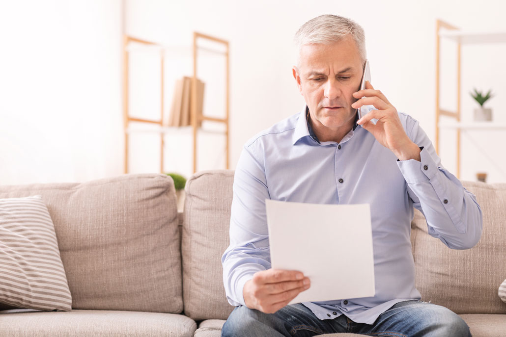 Man talking on phone while looking at paper