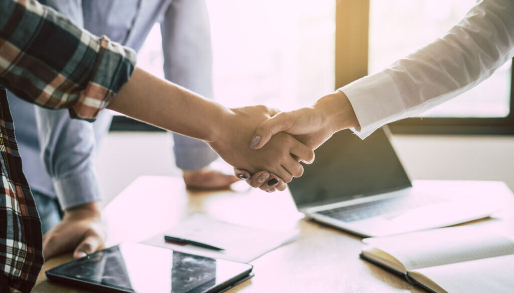 Two people shaking hands in office