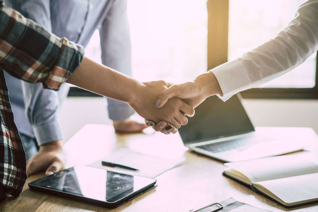 Two people shaking hands in office